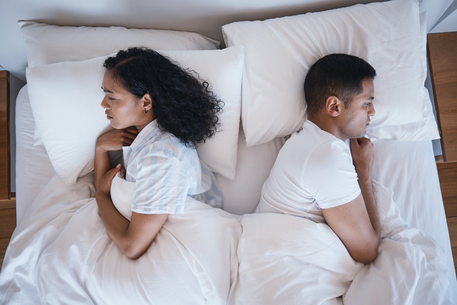 Paar liegt mit Abstand zueinander im Bett
