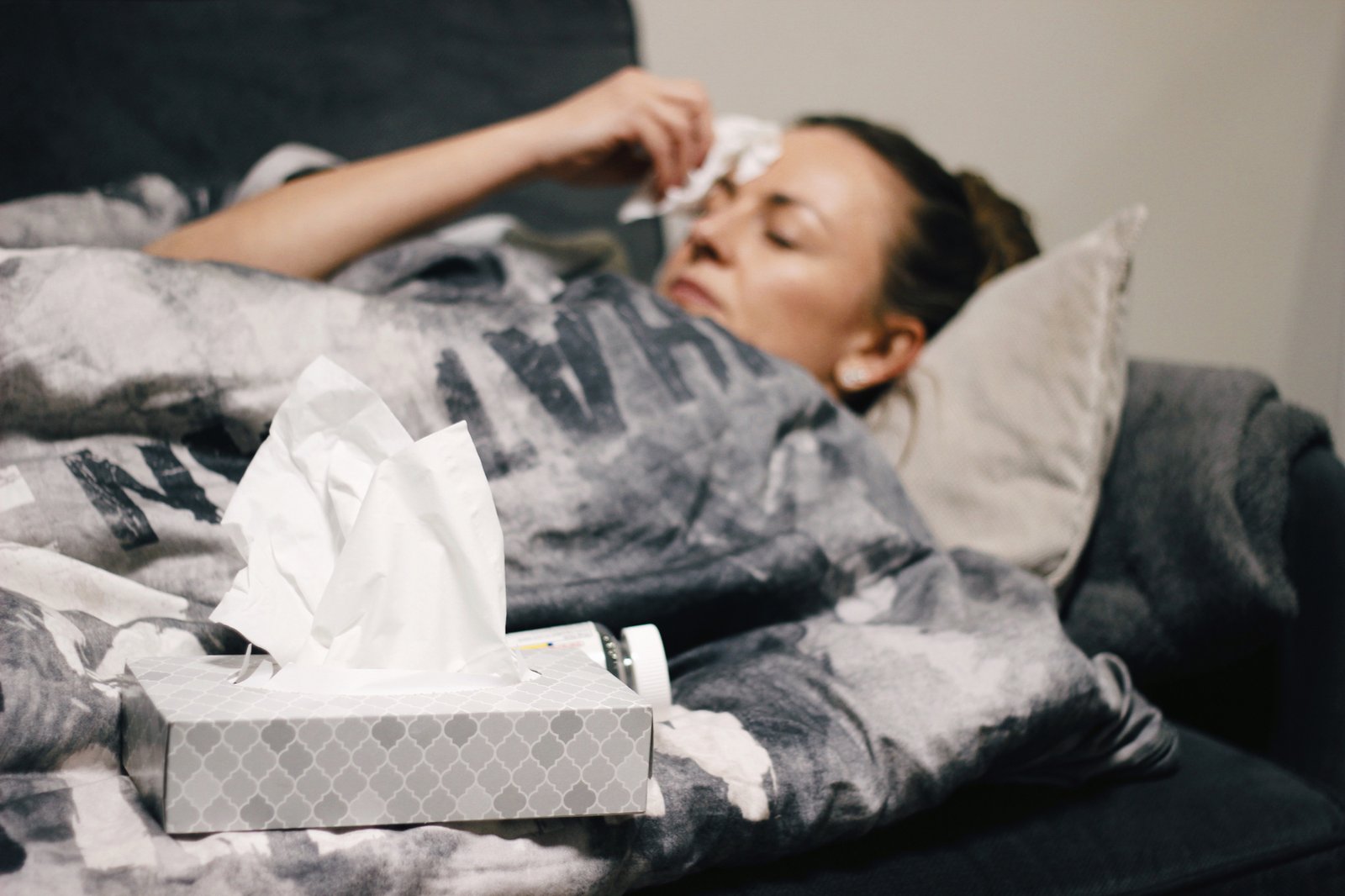 Kranke Person mit Taschentüchern im Bett